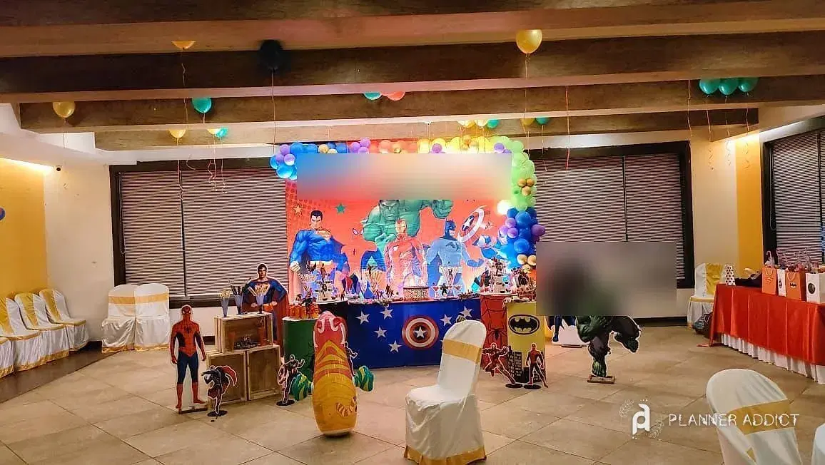 Superhero-theme birthday set-up with a balloon arch and character cut-outs
