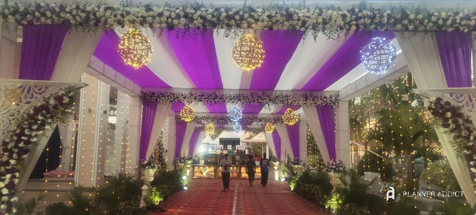 Walkway under purple and white drapes with lit flower balls
