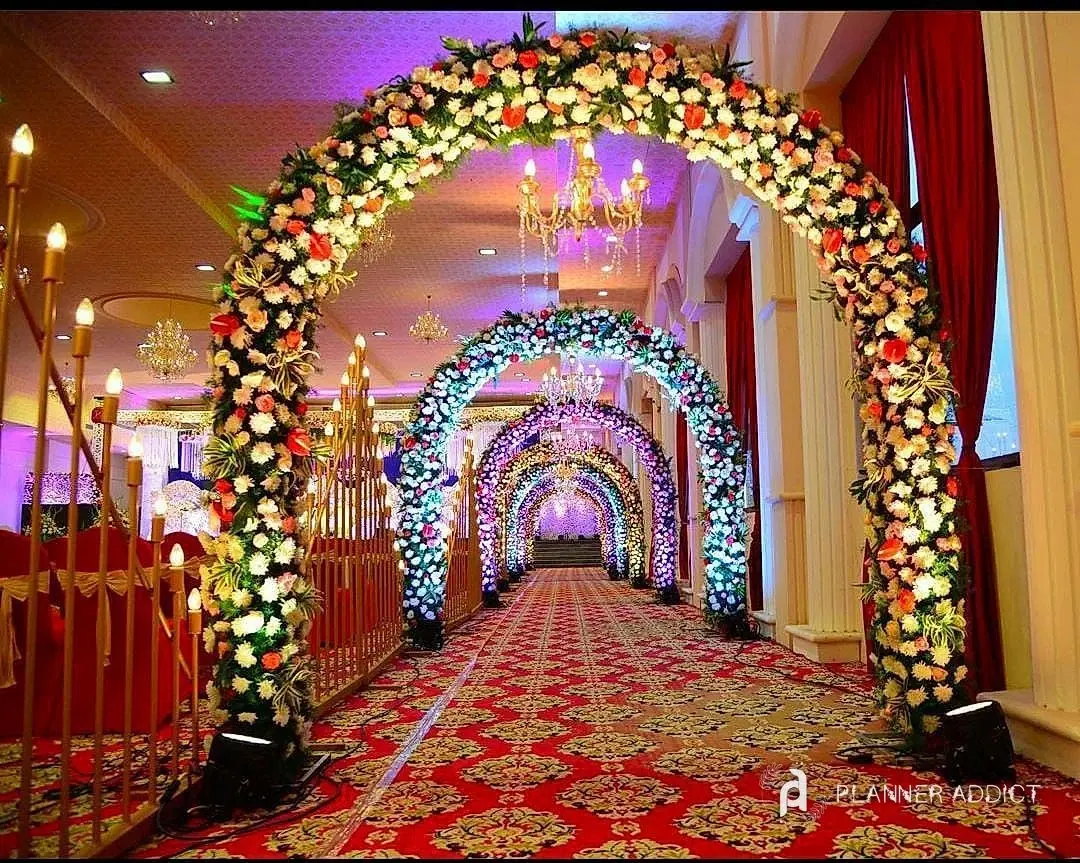 Tunnel of colourful flower arches over a red carpet
