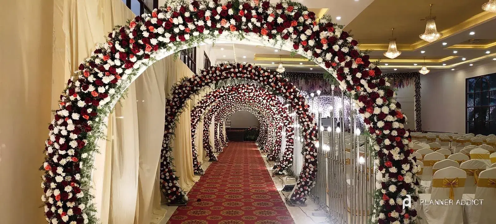 Tunnel of red and white rose arches over a red carpet