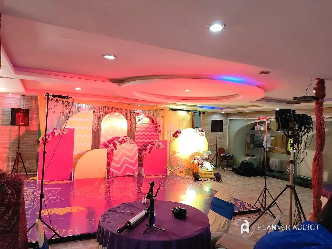 Hall with arched pink and peach backdrops, lights and speakers on stands