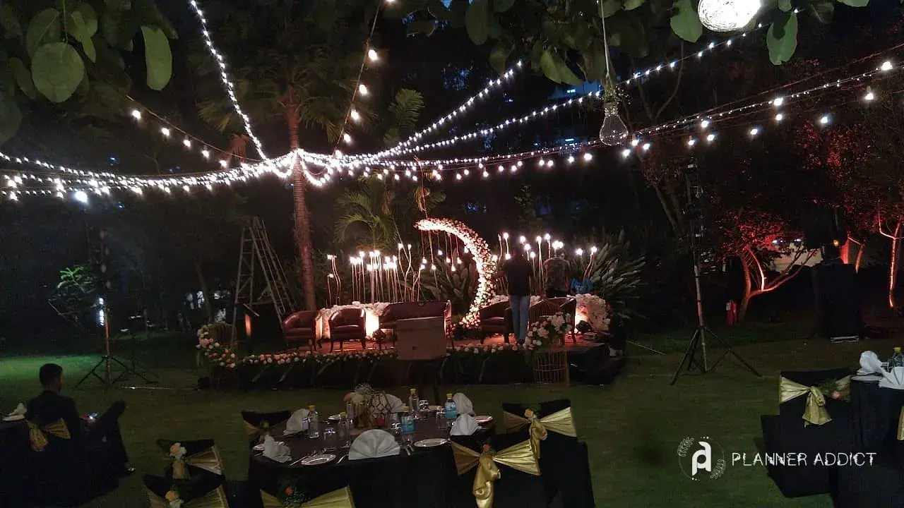 Garden dinner under string lights with a lit stage