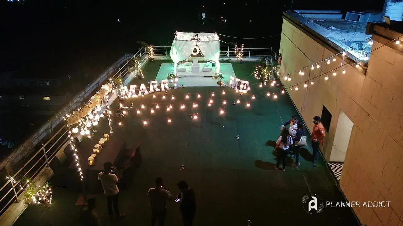 Rooftop proposal set-up with lit letters, candles and a canopy