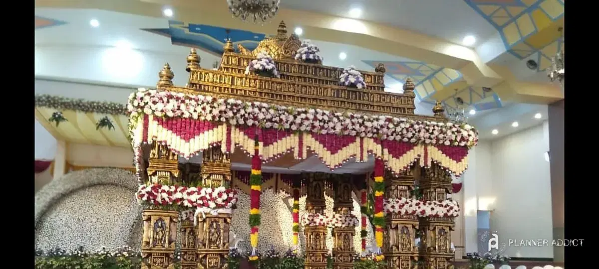 Carved gold mantapa hung with red and white flower garlands