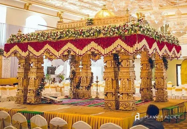 Mantapa with carved gold pillars and a red and white flower canopy