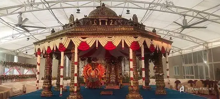 Temple-style mantapa with red and white drapes in a large hall