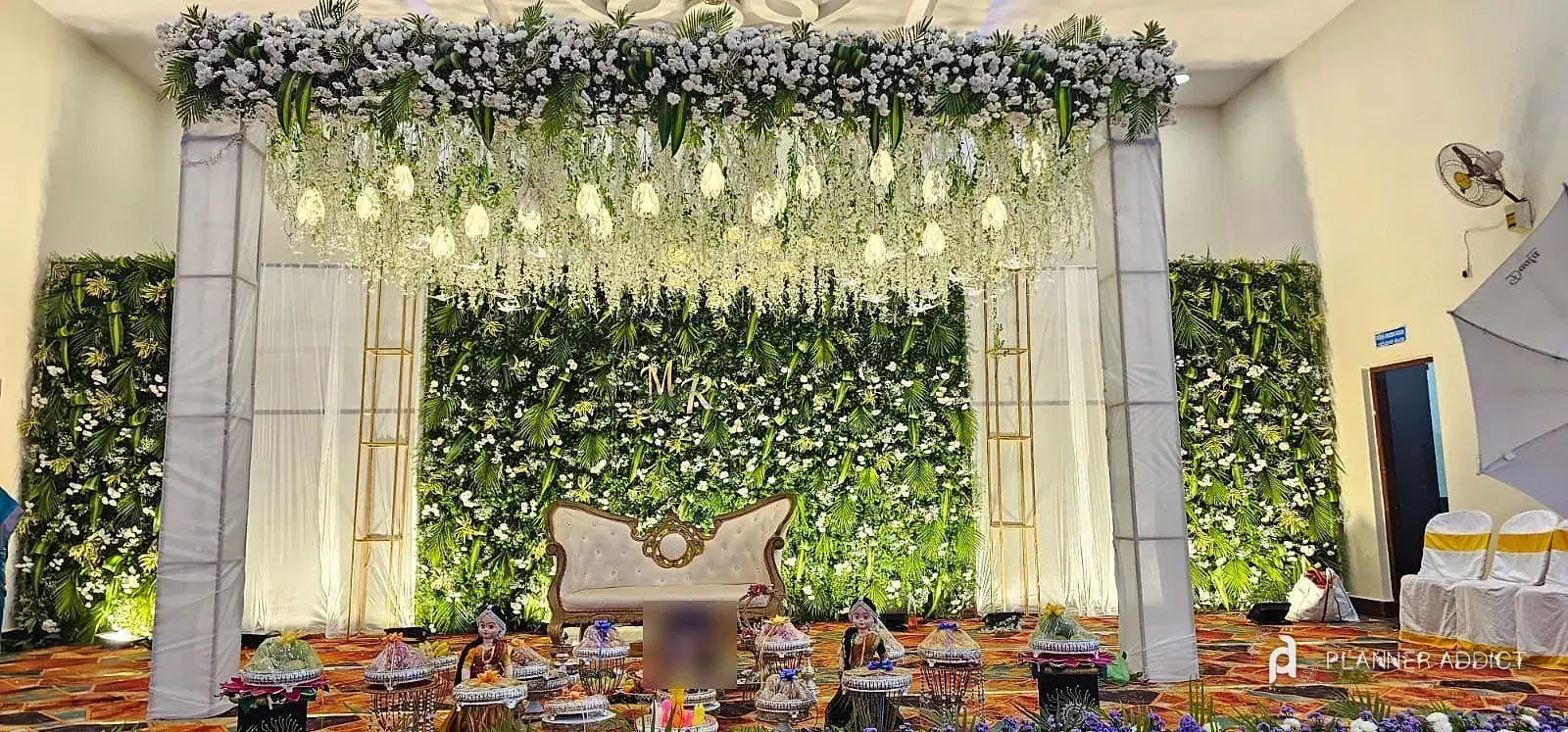 Stage with a green leaf wall, a white flower canopy and a white sofa