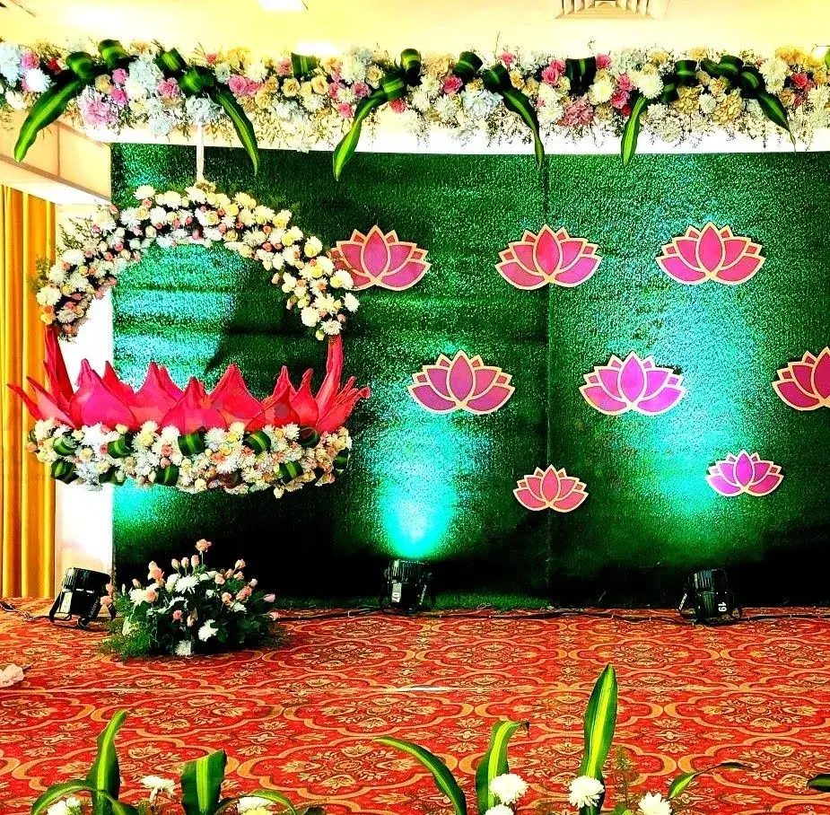 Green backdrop with lotus decorations for a naming ceremony