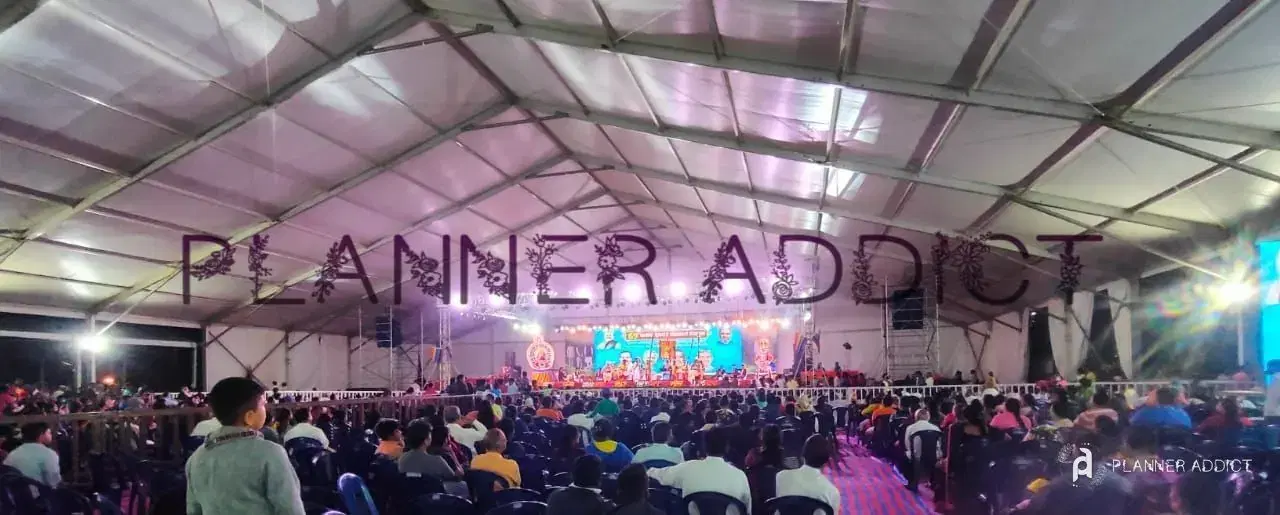 Large tented event with a lit stage and audience