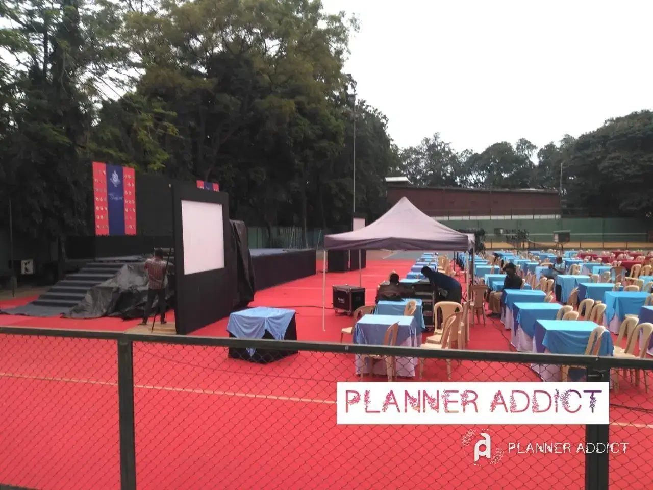 Outdoor event with a stage, screen and tables