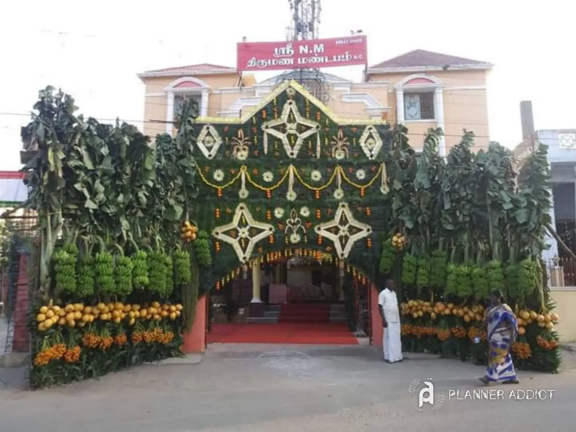Leaf-and-flower chappara at a marriage hall entrance, with banana trees, marigold strings and star motifs