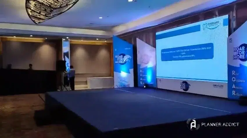 Hotel conference hall with a stage, a large screen and branded standees