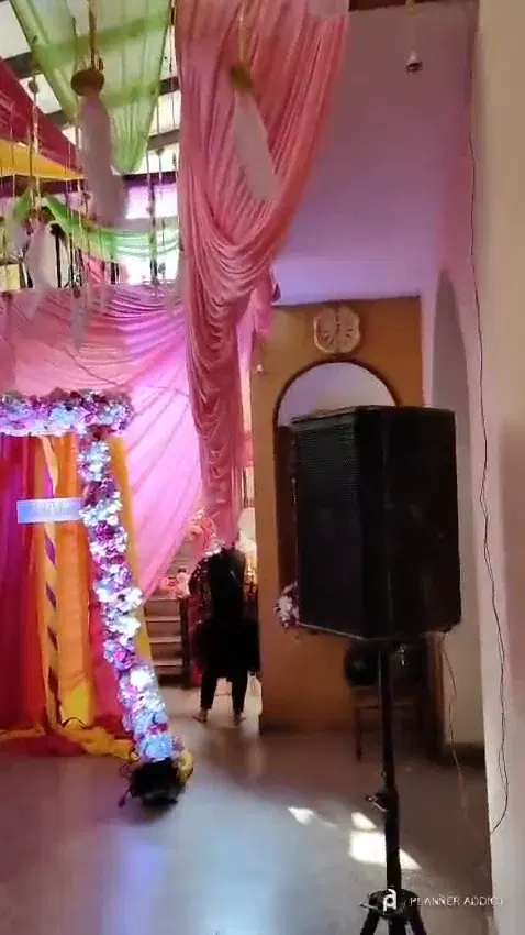 Hall decorated with pink and green drapes and a lit flower arch