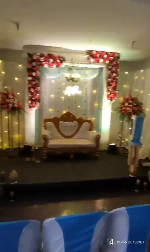 Reception hall with covered chairs, a speaker and the decorated stage
