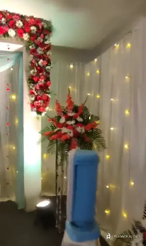 Reception stage with white curtain lights, red and white flowers and a carved sofa